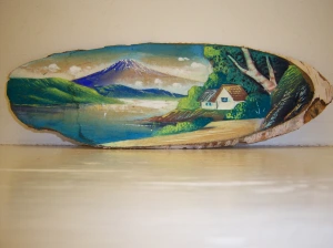 Photo of a carved wooden painting of a volcano and lake.